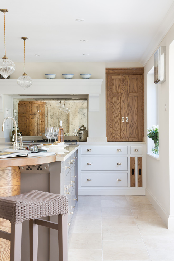 Inspiration for a medium sized classic single-wall open plan kitchen in London with a double-bowl sink, recessed-panel cabinets, metallic splashback, mirror splashback, stainless steel appliances, limestone flooring and an island.