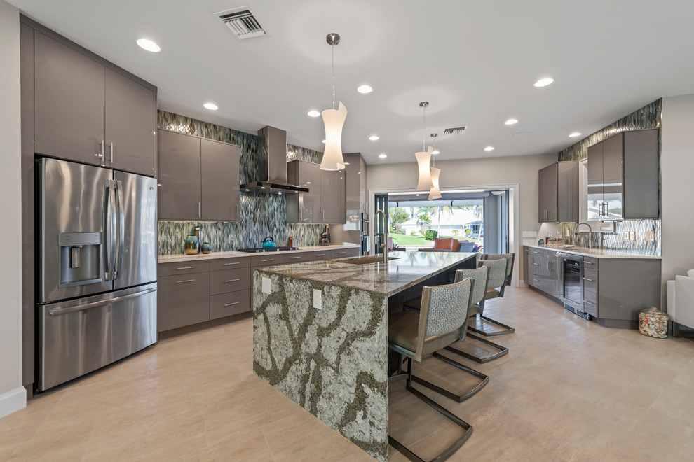 Moderne Küche mit Waschbecken, flächenbündigen Schrankfronten, grauen Schränken, Küchenrückwand in Grün, Küchengeräten aus Edelstahl, Kücheninsel, beigem Boden und grüner Arbeitsplatte in Miami