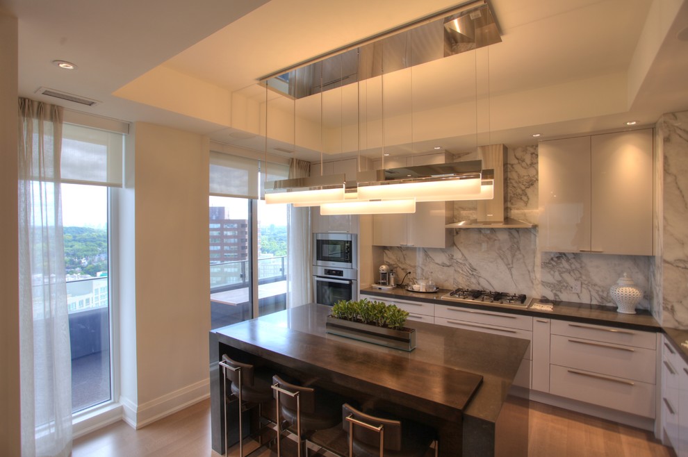 Small minimalist single-wall light wood floor enclosed kitchen photo in Toronto with an undermount sink, flat-panel cabinets, white cabinets, marble countertops, multicolored backsplash, stone slab backsplash, stainless steel appliances and an island
