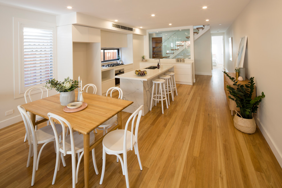 This is an example of a large contemporary l-shaped open plan kitchen in Sydney with flat-panel cabinets, white cabinets, granite worktops and an island.