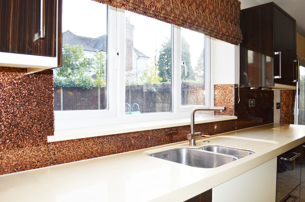 Bild på ett stort funkis kök och matrum, med släta luckor, skåp i mellenmörkt trä, marmorbänkskiva, orange stänkskydd, glaspanel som stänkskydd och en köksö