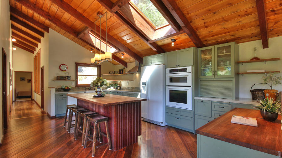 Large farmhouse l-shaped kitchen/diner in San Francisco with raised-panel cabinets, granite worktops, stainless steel appliances, medium hardwood flooring, an island, a belfast sink, brown floors and green cabinets.