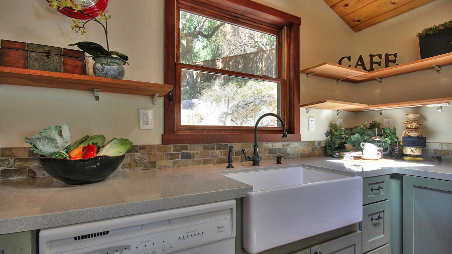 This is an example of a large rural l-shaped kitchen/diner in San Francisco with stainless steel appliances, a belfast sink, raised-panel cabinets, green cabinets, granite worktops, medium hardwood flooring, an island and brown floors.
