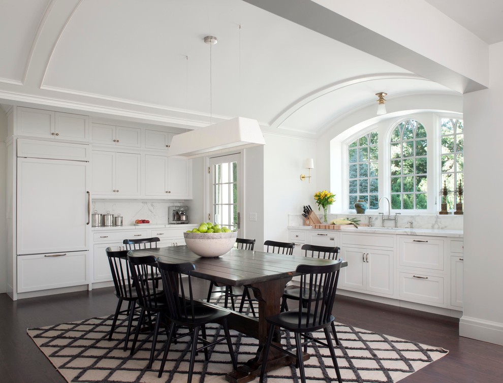 Inredning av ett klassiskt stort vit vitt kök, med skåp i shakerstil, vitt stänkskydd, integrerade vitvaror, en undermonterad diskho, marmorbänkskiva, stänkskydd i sten, mörkt trägolv och brunt golv