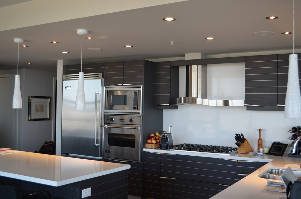 Foto på ett mellanstort funkis kök, med en dubbel diskho, luckor med infälld panel, skåp i mörkt trä, marmorbänkskiva, vitt stänkskydd, rostfria vitvaror, mörkt trägolv och en köksö