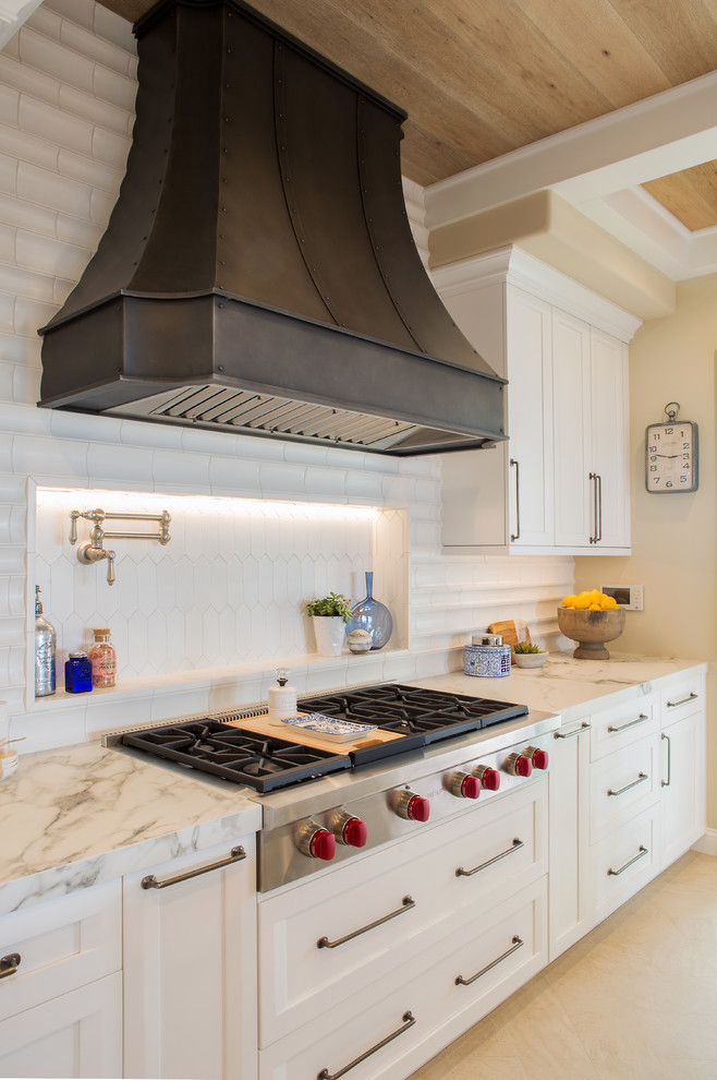 Inspiration for a large transitional l-shaped limestone floor and beige floor open concept kitchen remodel in Denver with a farmhouse sink, recessed-panel cabinets, white cabinets, quartz countertops, white backsplash, ceramic backsplash, paneled appliances, an island and white countertops