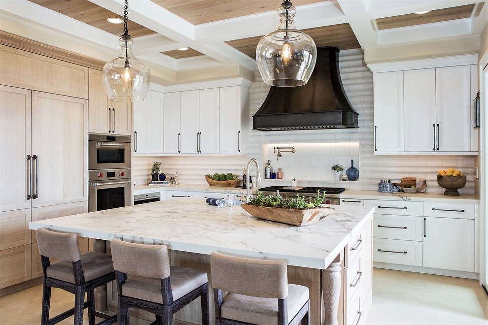 Design ideas for a large traditional l-shaped open plan kitchen in Denver with a belfast sink, recessed-panel cabinets, white cabinets, engineered stone countertops, white splashback, ceramic splashback, integrated appliances, limestone flooring, an island, beige floors and white worktops.