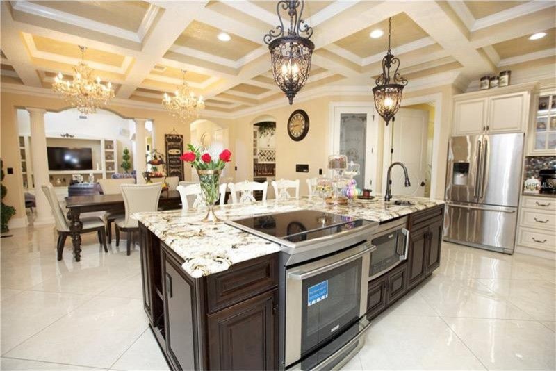 Foto på ett stort medelhavsstil kök, med en undermonterad diskho, luckor med upphöjd panel, vita skåp, granitbänkskiva, brunt stänkskydd, stänkskydd i mosaik, rostfria vitvaror, marmorgolv, en köksö och beiget golv