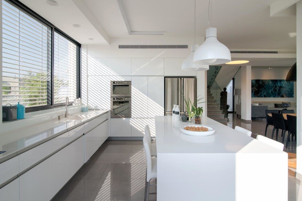 テルアビブにあるコンテンポラリースタイルのおしゃれなキッチン (フラットパネル扉のキャビネット、白いキャビネット、シルバーの調理設備) の写真