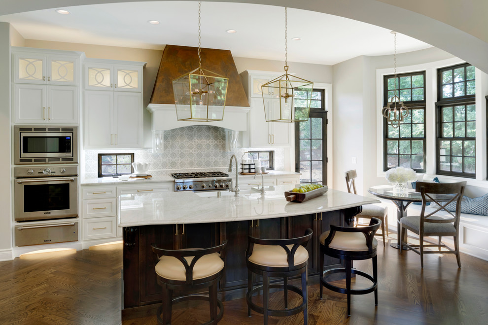 Large elegant l-shaped medium tone wood floor and brown floor eat-in kitchen photo with white cabinets, granite countertops, gray backsplash, ceramic backsplash, paneled appliances, an island, a farmhouse sink and recessed-panel cabinets