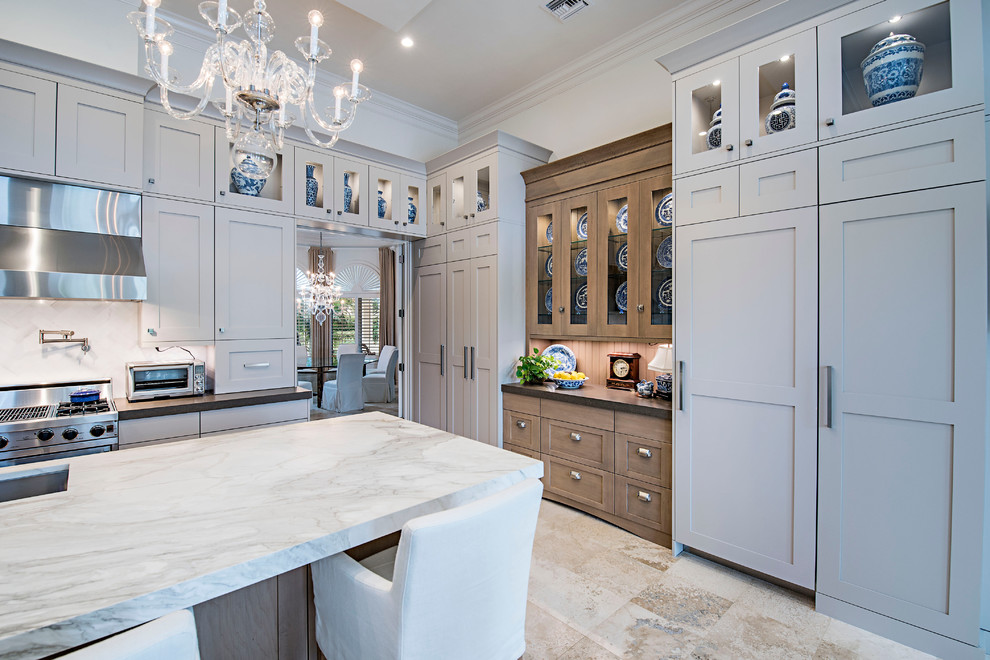 Large transitional l-shaped travertine floor eat-in kitchen photo in Miami with stainless steel appliances, an island, shaker cabinets, marble countertops, gray backsplash, stone slab backsplash, gray cabinets and an undermount sink