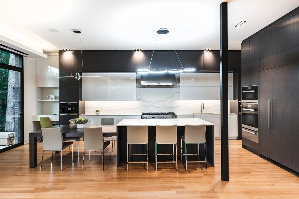 Contemporary kitchen/diner in Toronto with a single-bowl sink, flat-panel cabinets, white cabinets, white splashback, marble splashback, integrated appliances, light hardwood flooring, an island, beige floors and white worktops.