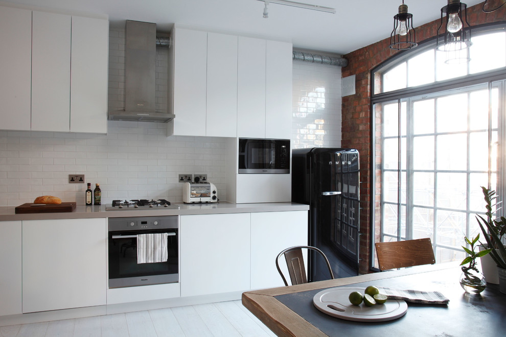 Ejemplo de cocina urbana grande abierta sin isla con puertas de armario blancas, salpicadero blanco y suelo de cemento