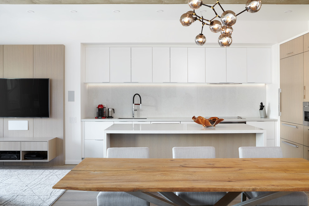 Eat-in kitchen - large modern l-shaped medium tone wood floor and brown floor eat-in kitchen idea in Toronto with an undermount sink, flat-panel cabinets, white cabinets, quartz countertops, gray backsplash, stone slab backsplash, paneled appliances, an island and white countertops
