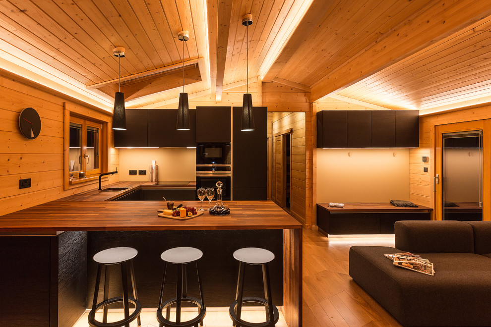 Offene, Mittelgroße Moderne Küche mit flächenbündigen Schrankfronten, schwarzen Schränken, braunem Holzboden, Halbinsel und braunem Boden in Hampshire