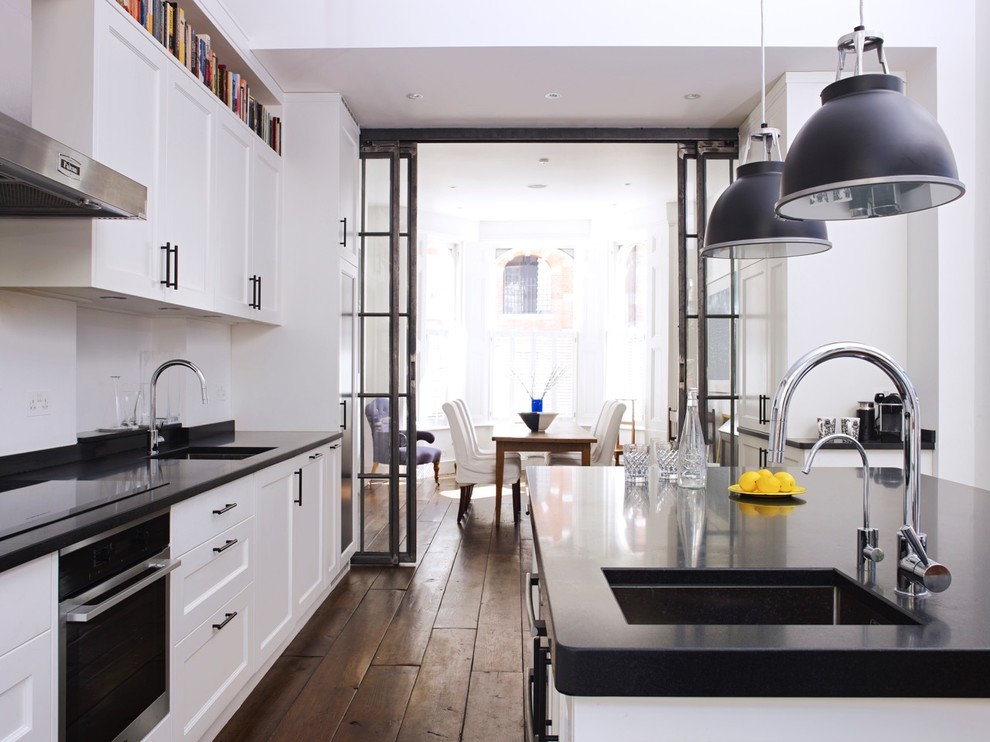 Example of a large trendy eat-in kitchen design in London with shaker cabinets, black appliances and an island