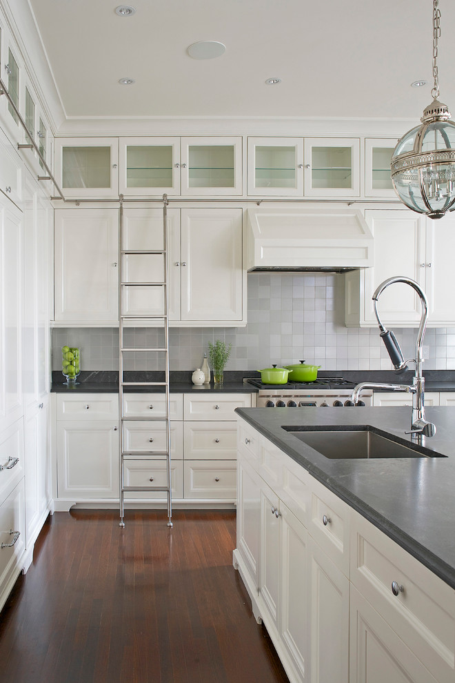 Inspiration för stora klassiska kök, med luckor med infälld panel, vita skåp, marmorbänkskiva, en undermonterad diskho, vitt stänkskydd, stänkskydd i metallkakel, integrerade vitvaror, mellanmörkt trägolv och en köksö
