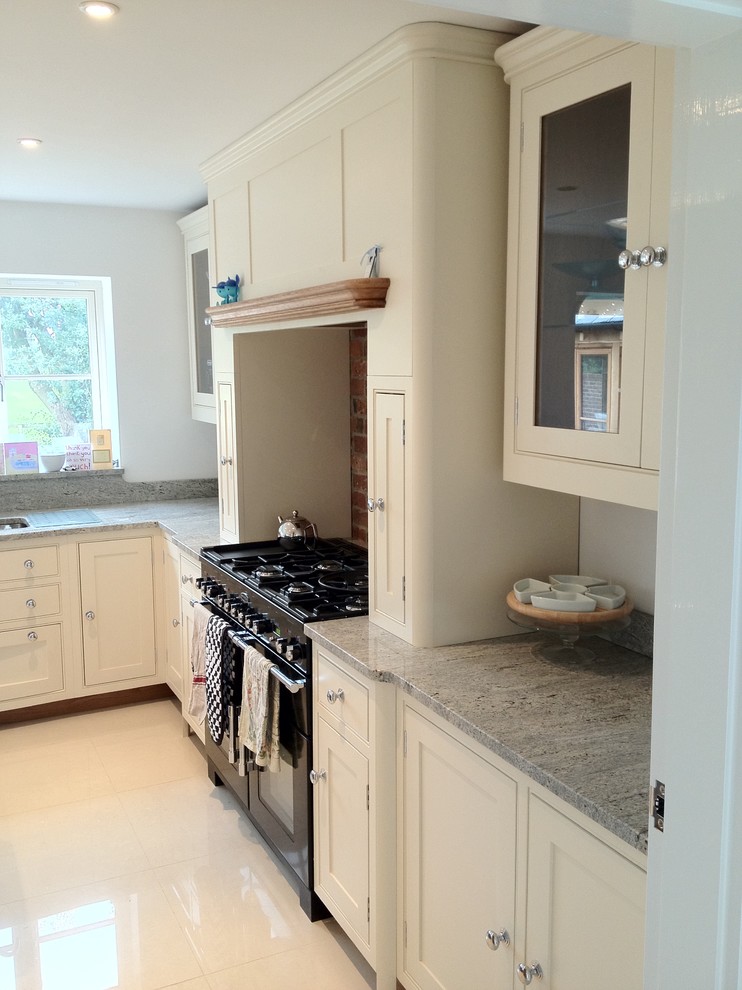 This is an example of a medium sized classic l-shaped kitchen/diner in Cambridgeshire with a double-bowl sink, shaker cabinets, granite worktops, red splashback, stone tiled splashback, stainless steel appliances, ceramic flooring and an island.