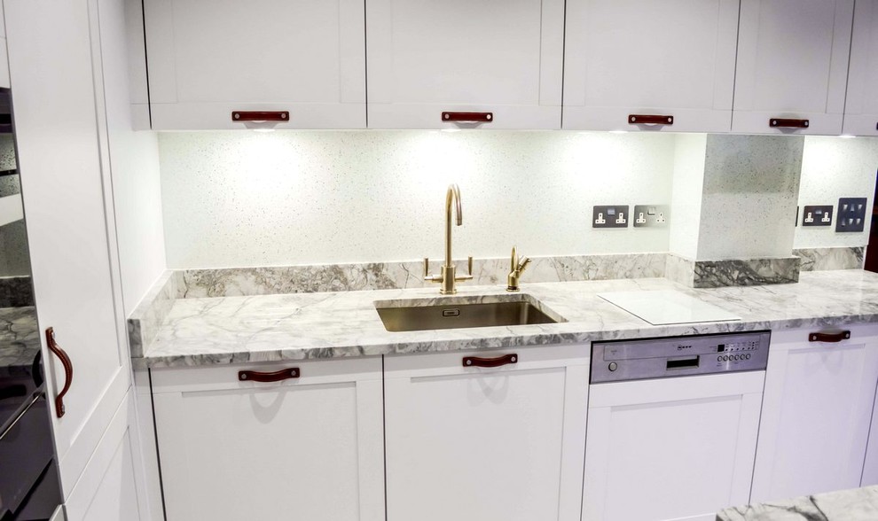 Cette photo montre une cuisine moderne avec une crédence blanche et une crédence en feuille de verre.