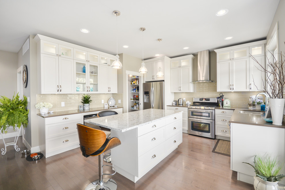 Kitchen - traditional u-shaped medium tone wood floor kitchen idea in Vancouver with an undermount sink, shaker cabinets, white cabinets, beige backsplash, stainless steel appliances and an island
