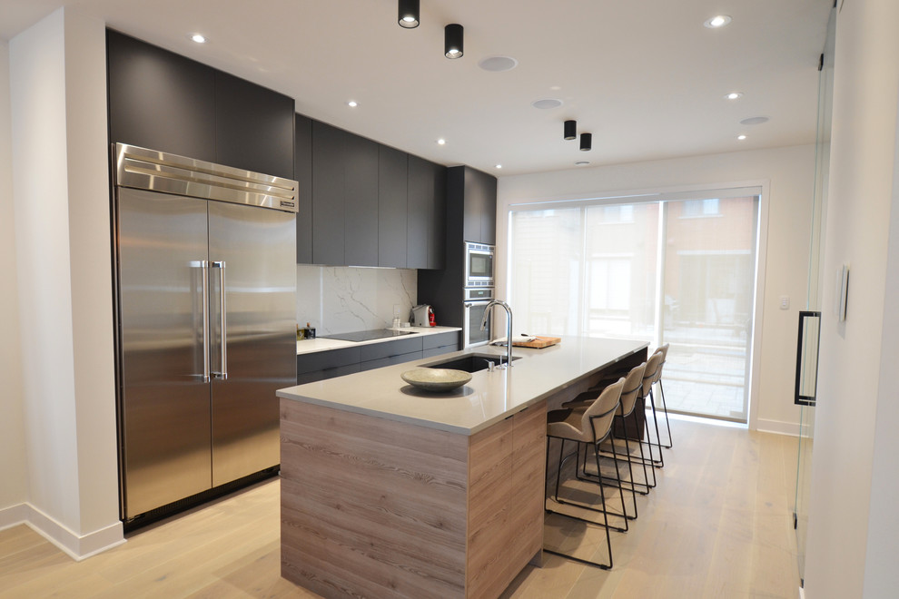 Photo of a medium sized modern single-wall kitchen/diner in Montreal with a submerged sink, flat-panel cabinets, grey cabinets, engineered stone countertops, white splashback, stainless steel appliances, light hardwood flooring, an island, beige floors and multicoloured worktops.