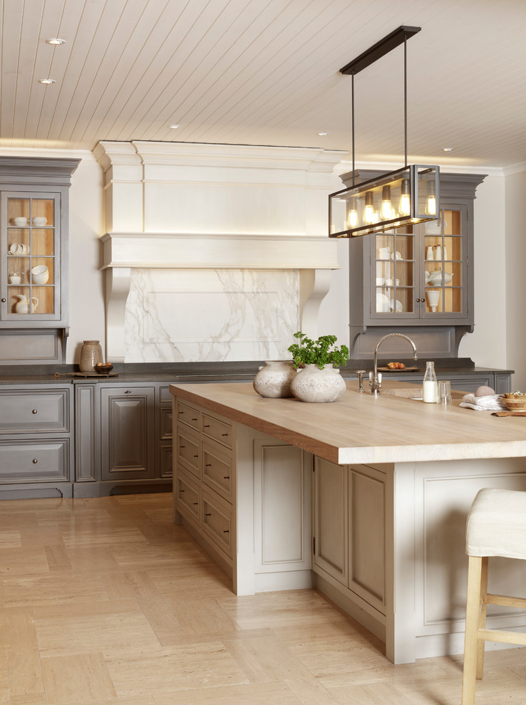 Inredning av ett stort kök och matrum, med en dubbel diskho, luckor med upphöjd panel, skåp i slitet trä, träbänkskiva, vitt stänkskydd, stänkskydd i marmor, rostfria vitvaror, kalkstensgolv och en köksö