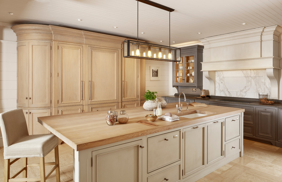 Exempel på ett stort klassiskt kök och matrum, med en dubbel diskho, luckor med upphöjd panel, skåp i slitet trä, träbänkskiva, vitt stänkskydd, stänkskydd i marmor, rostfria vitvaror, kalkstensgolv, en köksö och beiget golv
