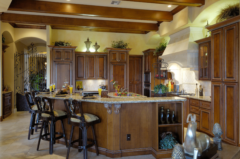Example of a mid-sized tuscan l-shaped ceramic tile and beige floor eat-in kitchen design in Tampa with raised-panel cabinets, dark wood cabinets, granite countertops, white backsplash, ceramic backsplash, paneled appliances and two islands