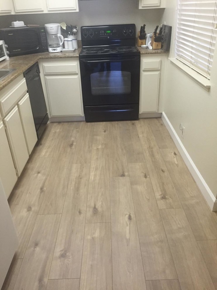 Photo of a small contemporary single-wall enclosed kitchen in Sacramento with flat-panel cabinets, white cabinets, granite worktops, black appliances, vinyl flooring and no island.