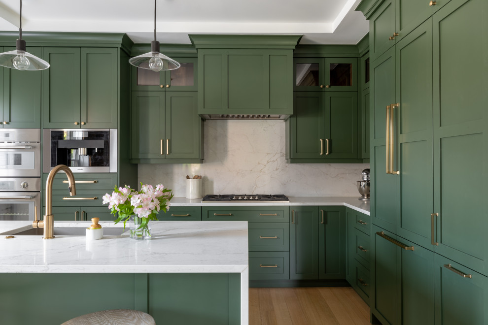 Inspiration for a large transitional l-shaped light wood floor, brown floor and tray ceiling eat-in kitchen remodel in Detroit with an undermount sink, shaker cabinets, green cabinets, quartz countertops, white backsplash, quartz backsplash, stainless steel appliances, an island and white countertops