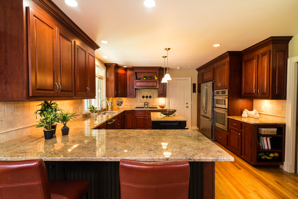Inspiration for a mid-sized timeless l-shaped medium tone wood floor kitchen remodel in Boston with an undermount sink, raised-panel cabinets, dark wood cabinets, granite countertops, beige backsplash, ceramic backsplash and an island