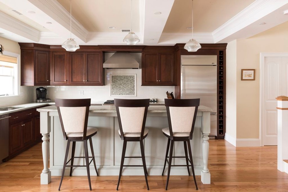 Inspiration for a transitional l-shaped medium tone wood floor kitchen remodel in Boston with an undermount sink, recessed-panel cabinets, dark wood cabinets, multicolored backsplash, mosaic tile backsplash, stainless steel appliances and an island