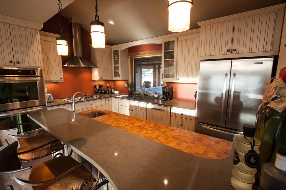 Foto på ett mellanstort lantligt kök, med en undermonterad diskho, släta luckor, vita skåp, träbänkskiva, orange stänkskydd, rostfria vitvaror, mellanmörkt trägolv, en köksö och brunt golv