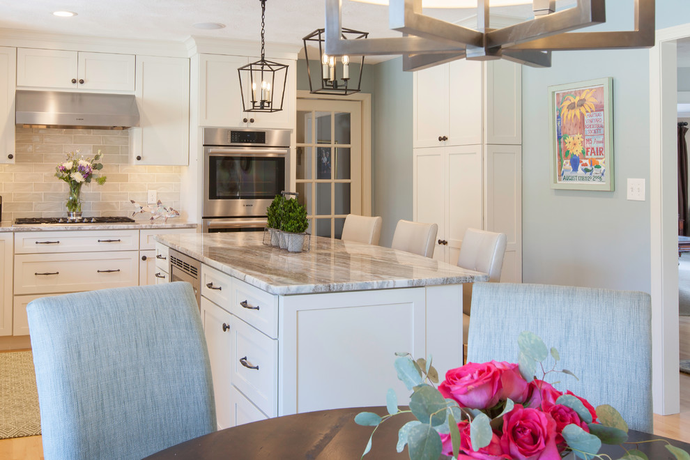 Eat-in kitchen - large transitional l-shaped light wood floor eat-in kitchen idea in Boston with an undermount sink, shaker cabinets, white cabinets, granite countertops, green backsplash, glass tile backsplash, stainless steel appliances and an island