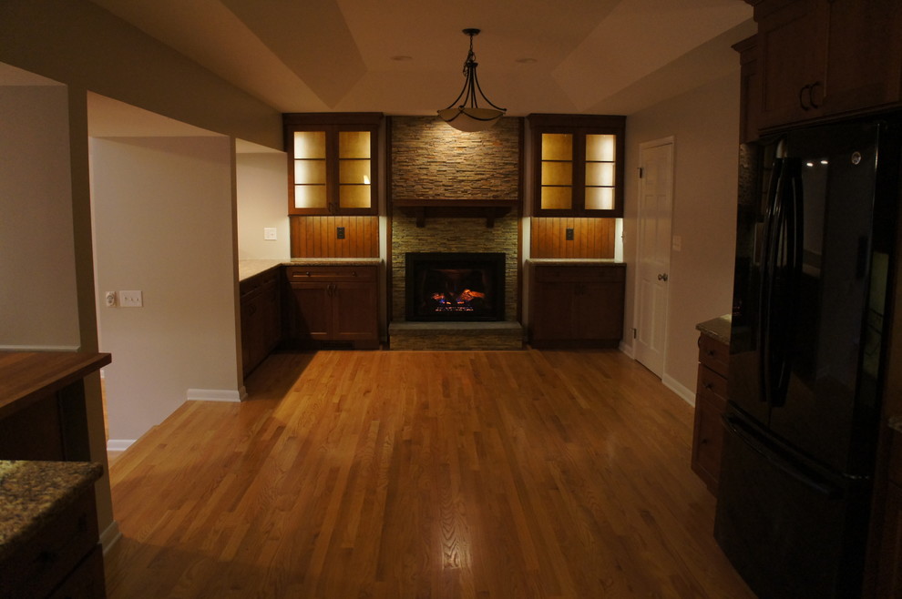 Example of a large trendy u-shaped light wood floor eat-in kitchen design in Boston with dark wood cabinets, quartz countertops, beige backsplash, ceramic backsplash, black appliances and an island