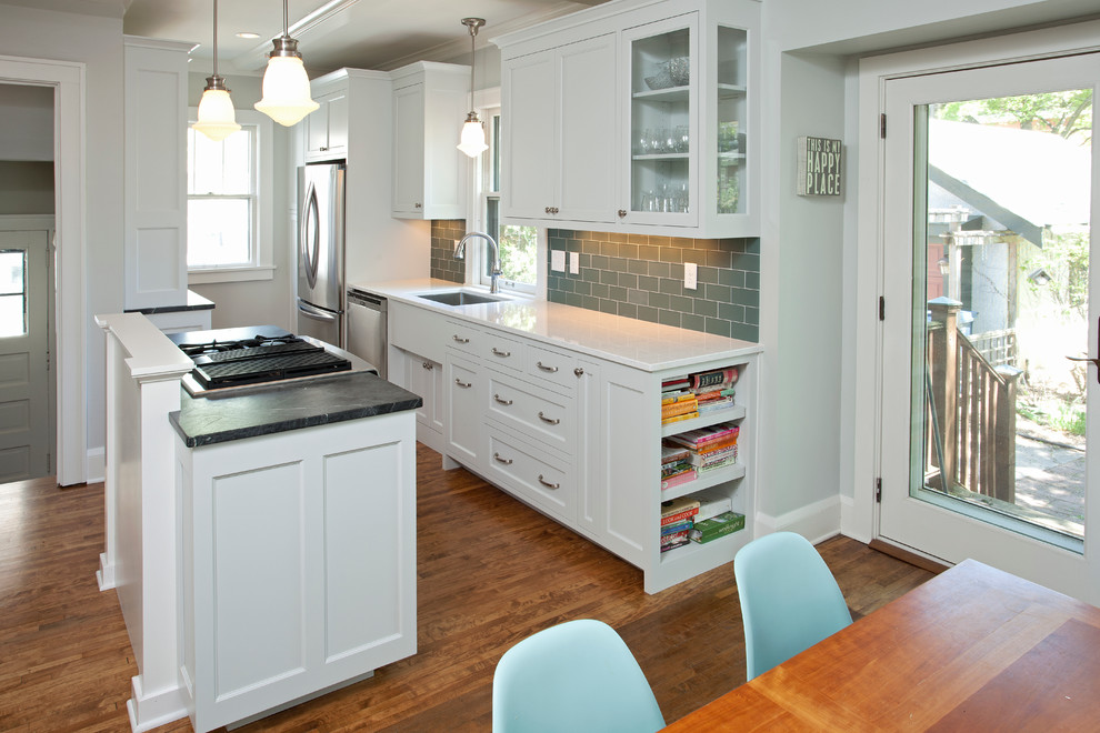 Foto på ett litet amerikanskt kök, med en enkel diskho, luckor med infälld panel, bänkskiva i täljsten, grönt stänkskydd, rostfria vitvaror, mellanmörkt trägolv, en köksö, stänkskydd i tunnelbanekakel, beiget golv och vita skåp