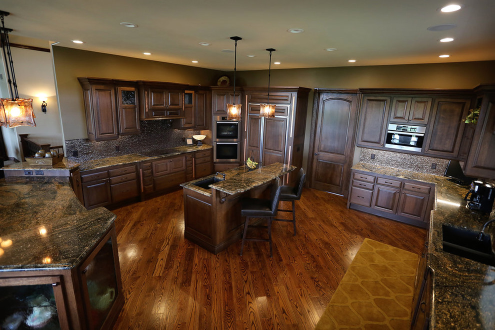 Eat-in kitchen - large country l-shaped medium tone wood floor eat-in kitchen idea in Other with an undermount sink, raised-panel cabinets, dark wood cabinets, granite countertops, multicolored backsplash, matchstick tile backsplash, stainless steel appliances and a peninsula