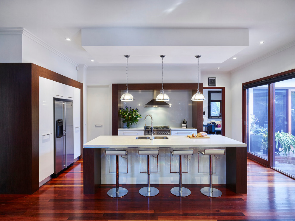 Inspiration for a large contemporary u-shaped kitchen in Melbourne with a double-bowl sink, white cabinets, stainless steel appliances, medium hardwood flooring and an island.