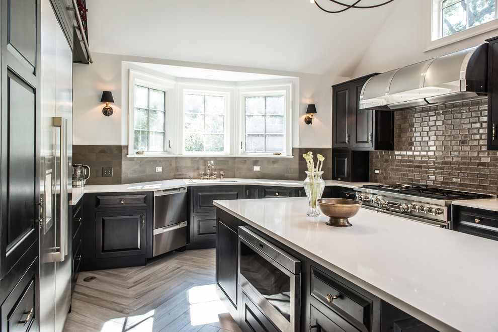 Large transitional u-shaped porcelain tile eat-in kitchen photo in New York with raised-panel cabinets, black cabinets, stainless steel appliances, an island, an undermount sink, solid surface countertops, gray backsplash and ceramic backsplash