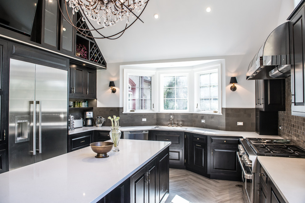 This is an example of a large classic u-shaped kitchen/diner in New York with raised-panel cabinets, black cabinets, stainless steel appliances, an island, a submerged sink, composite countertops, grey splashback, ceramic splashback and porcelain flooring.
