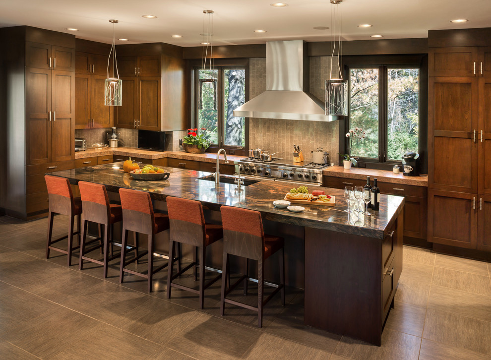 Eat-in kitchen - mid-sized craftsman l-shaped limestone floor eat-in kitchen idea in Milwaukee with a farmhouse sink, recessed-panel cabinets, white cabinets, granite countertops, brown backsplash, ceramic backsplash, paneled appliances and an island