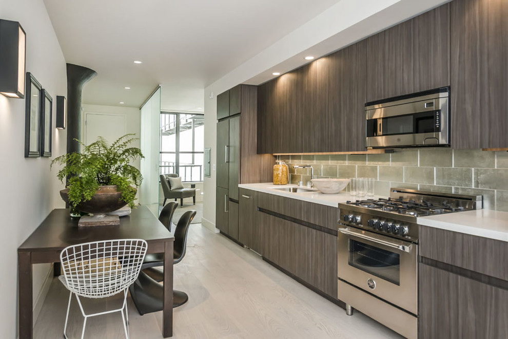 Immagine di una cucina minimal con lavello sottopiano, ante lisce, paraspruzzi verde, elettrodomestici in acciaio inossidabile, pavimento in gres porcellanato e pavimento beige