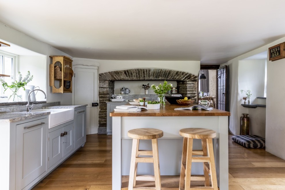 Photo of a medium sized rural l-shaped kitchen in Devon with a belfast sink, grey cabinets, granite worktops, an island, beige floors, grey worktops, shaker cabinets and medium hardwood flooring.