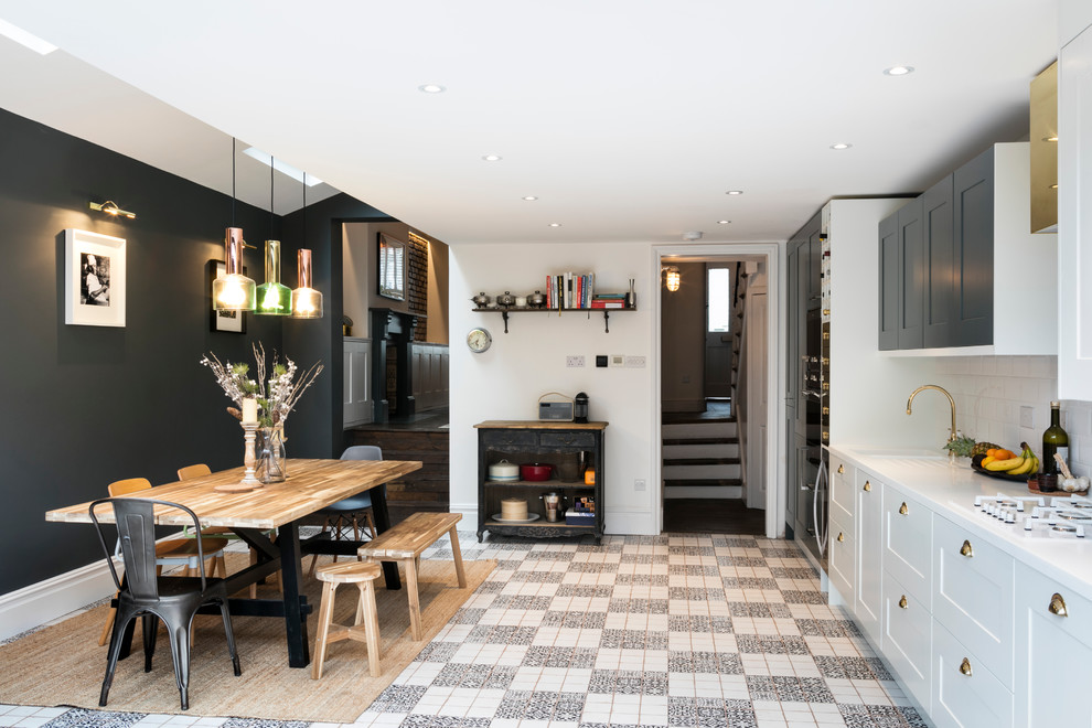 Photo of a contemporary kitchen/diner in London with a built-in sink, white cabinets, white splashback, ceramic splashback and white appliances.