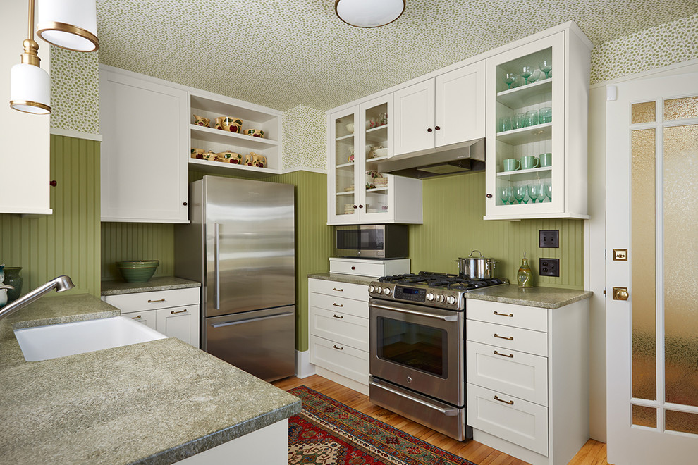 Bild på ett avskilt amerikanskt u-kök, med en rustik diskho, skåp i shakerstil, vita skåp, granitbänkskiva, grönt stänkskydd, stänkskydd i trä, rostfria vitvaror, mellanmörkt trägolv, en halv köksö och brunt golv