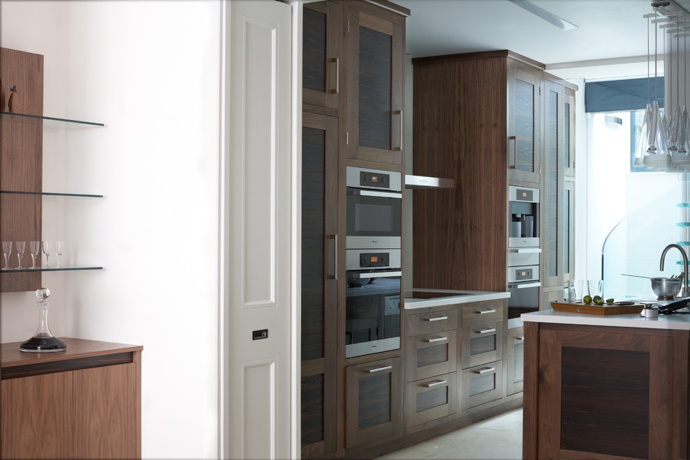 This is an example of a large contemporary galley kitchen/diner in West Midlands with a submerged sink, recessed-panel cabinets, dark wood cabinets, granite worktops, glass sheet splashback, stainless steel appliances, ceramic flooring and an island.