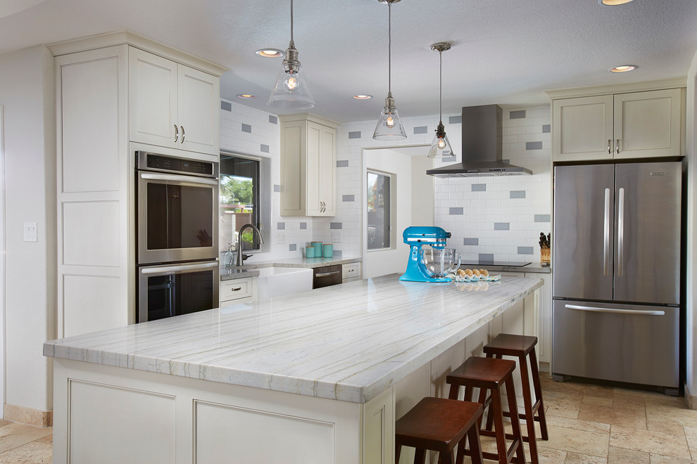 Inredning av ett modernt grå grått kök med öppen planlösning, med en rustik diskho, luckor med infälld panel, vita skåp, bänkskiva i kvartsit, vitt stänkskydd, stänkskydd i keramik, rostfria vitvaror, travertin golv och en köksö
