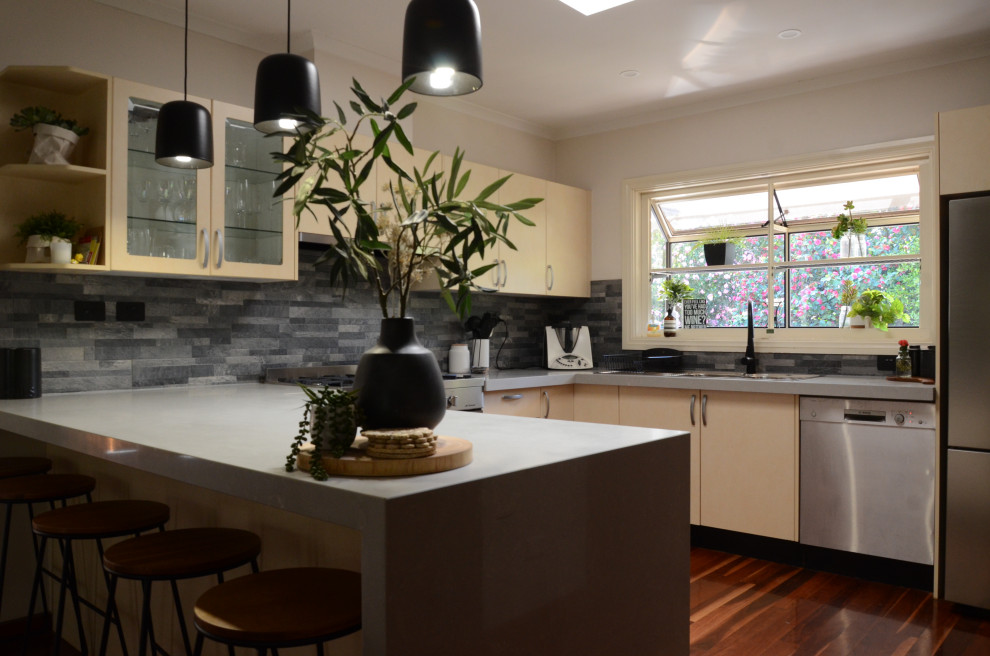 Inredning av ett modernt mellanstort grå grått kök, med en dubbel diskho, gula skåp, bänkskiva i kvarts, grått stänkskydd, stänkskydd i skiffer, rostfria vitvaror och en köksö