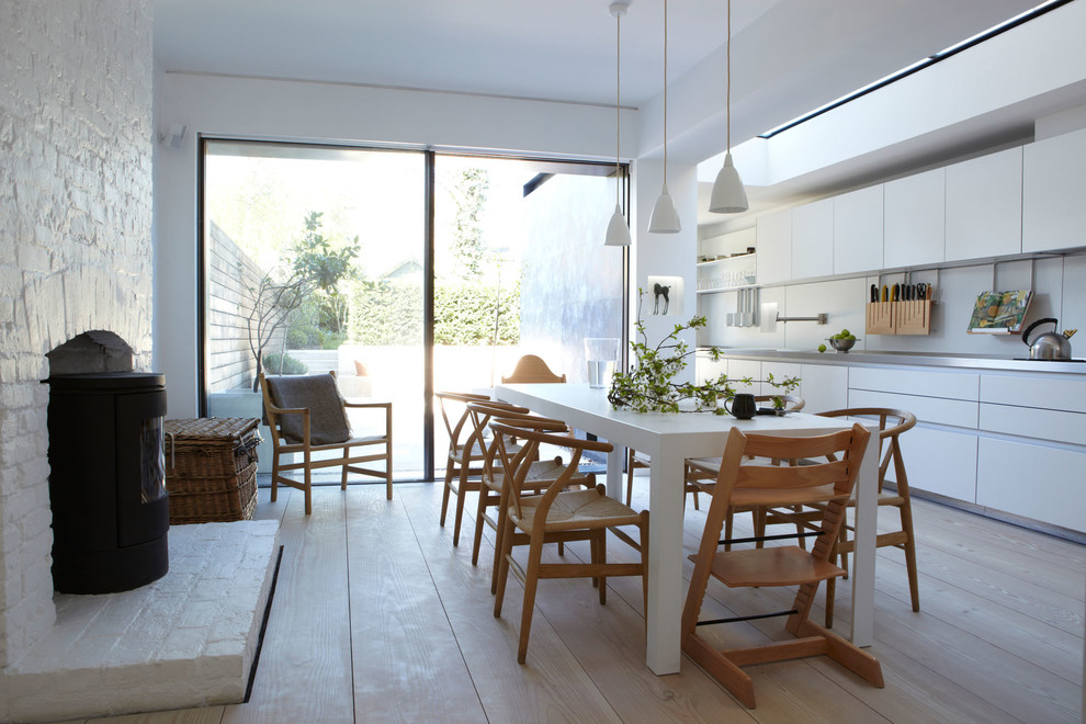 Einzeilige Skandinavische Wohnküche mit flächenbündigen Schrankfronten, weißen Schränken, Küchenrückwand in Weiß und hellem Holzboden in London