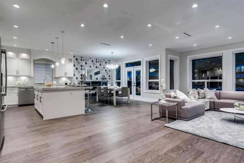 Moderne Wohnküche in L-Form mit Schrankfronten im Shaker-Stil, weißen Schränken, Küchenrückwand in Grau, Küchengeräten aus Edelstahl, braunem Holzboden und Kücheninsel in Vancouver